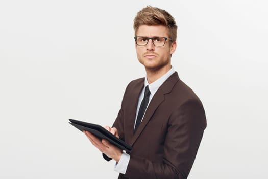 Portrait, tablet and glasses with a business man in studio isolated on a white background for management. Corporate, technology and planning with a serious young employee in eyewear for research