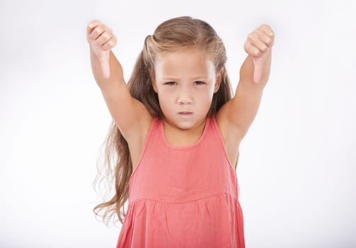 Thumbs down, girl or portrait of kid in studio for bad news, unhappy emoji sign and vote no on white background. Disappointed child, negative review and fail for decision, wrong results and rejection