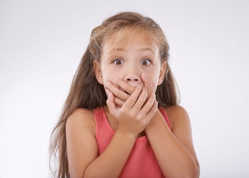 Shock, portrait and hands over mouth, girl kid with reaction and unexpected news with surprise on white background. Announcement, alarm and youth in studio with facial expression and wow for drama