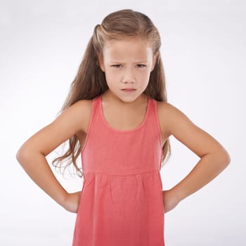 Child, portrait and unhappy grumpy in studio or bad mood discipline or development, trouble or angry. Female person, hands and hips in frustration for girl kid as white background, attitude or mockup