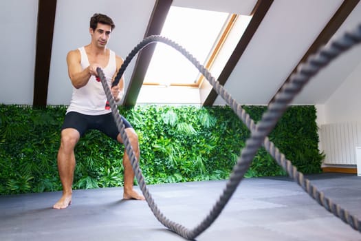 Athletic man training with battle ropes