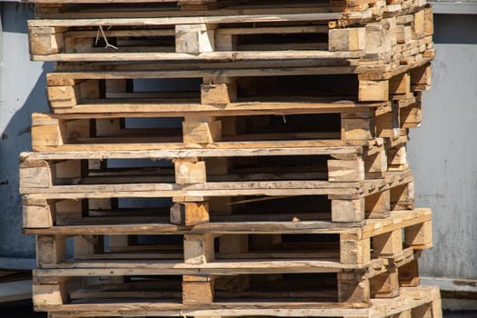 Used wooden pallets stacked along a wall in a warehouse lot