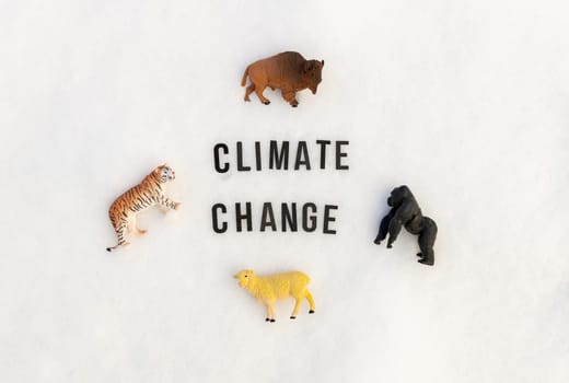 The phrase climate change and four toy wild animals on the snow.