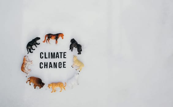 The phrase climate change and eight toy wild animals on the snow.
