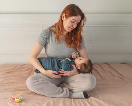 Woman with postpartum depression sitting on bed and holding newborn son.