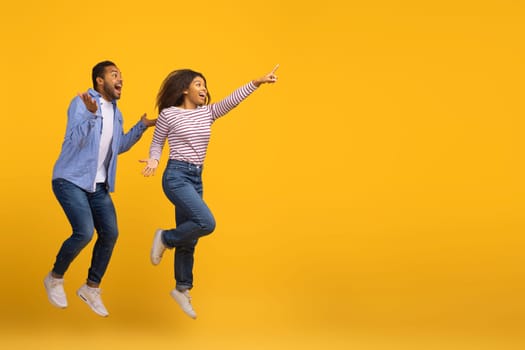 Cool Offer. Excited Joyful Black Couple Jumping And Pointing At Copy Space