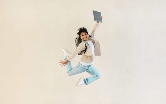 Carefree chinese man with computer in his hand jumping up