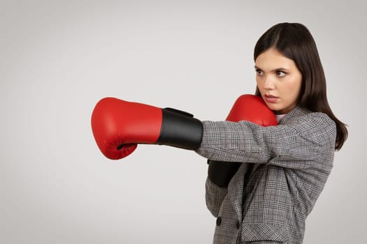 Businesswoman in defensive stance with boxing gloves