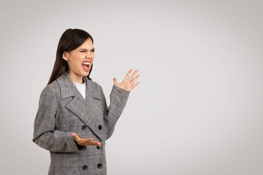 Angry woman in gray blazer shouting with hand gesture