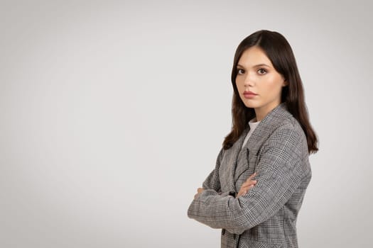 Confident young woman in a plaid blazer, arms crossed