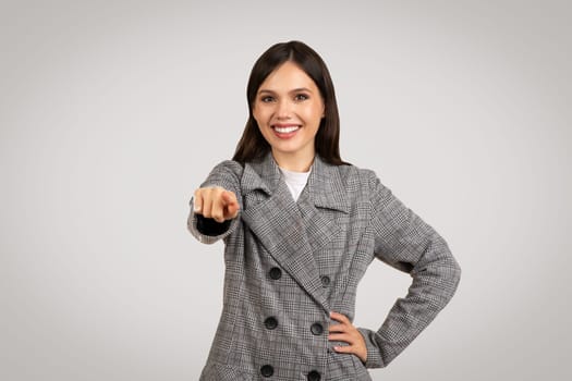 Smiling woman in plaid pointing directly at camera