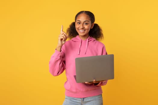 black girl with laptop having idea pointing finger up, studio