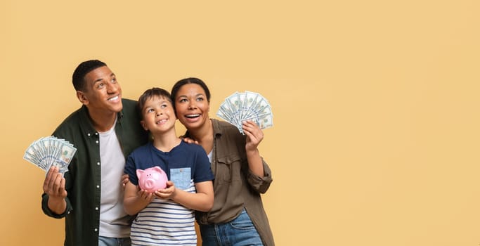 Black family holding money cash and piggy bank, copy space