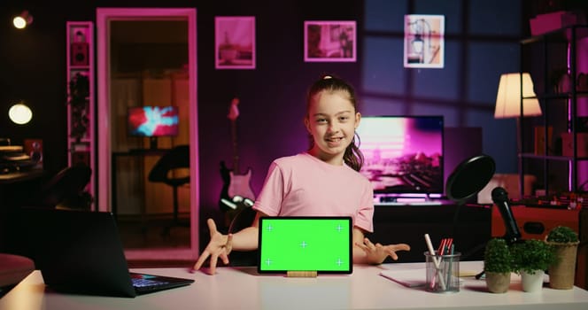 Smiling daughter filming online content with her parent using green screen tablet from sponsor