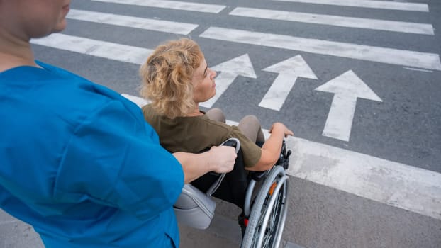 Rear view of a nurse helping an elderly woman in a wheelchair cross the road.