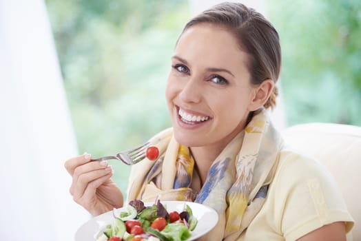 Woman, smile and eating salad in home for diet, health and wellness with pride at lunch in lounge. Person, food and hungry with vegetables, plate and nutrition with vitamins, fiber and relax in house