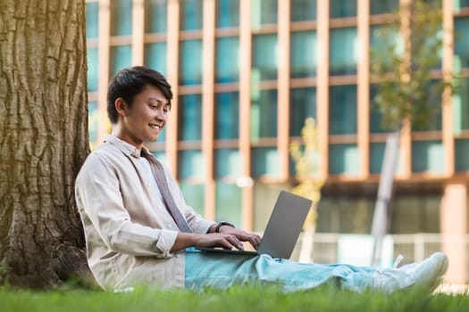 Relaxed young asian guy freelancer working at park