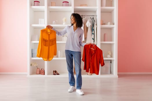 Woman comparing yellow and red tops in closet