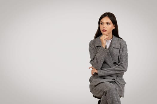 Pensive businesswoman in checkered suit, contemplating