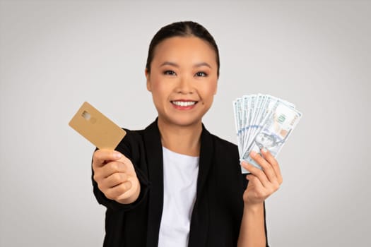 Smiling Asian businesswoman offers a choice between cash and credit card