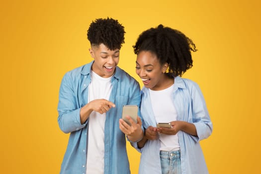 A young woman and man share a joyful moment looking at a smartphone together