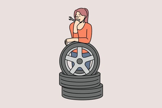 Woman auto mechanic prepares to replace car wheels during vehicle maintenance or repair