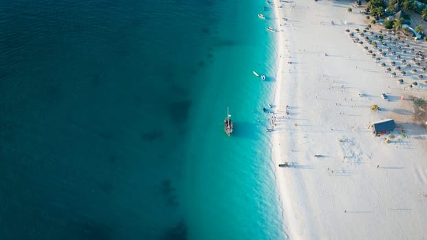 Drone view of dhow boat in the green ocean and wonderful white sandy beach