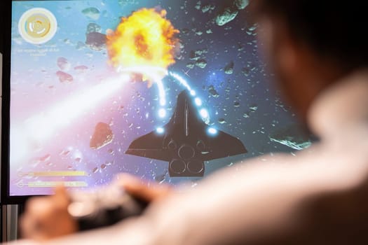 Man in living room playing science fiction videogame on gaming console, shooting lasers
