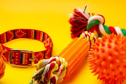 Dog collar and toys on yellow background