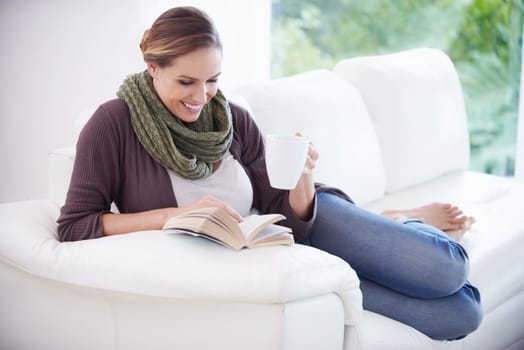 Happy woman, book and reading with coffee on sofa for story, novel or knowledge in living room at home. Lady, fiction books and drinking cup of tea for literature, hobby or comfortable break on couch