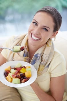 Healthy food, happy woman in portrait and fruit in salad for diet, organic meal and relax on sofa with smile for weight loss. Vegan, gut health and wellness, eating for nutrition with vitamins