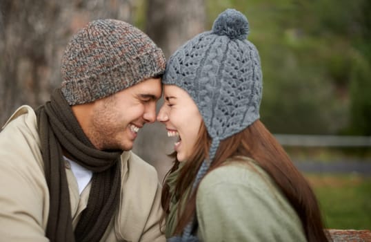 Face, love and laughing with couple on park bench for vacation, romance or bonding together outdoor. Smile, happy or funny with young man and woman dating or having fun in nature with winter weather