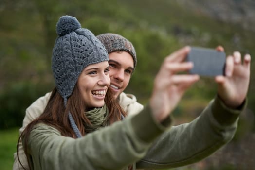 Couple, selfie and smile while hiking in nature, smartphone and capture moment in outdoors. People, happy and picture for memory and exploring wilderness, trekking and photograph for social media