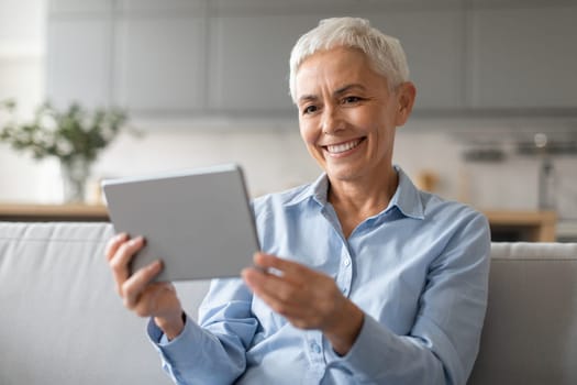Portrait Of Happy Mature Lady Using Digital Tablet Browsing Internet