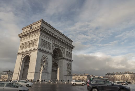 Famous Arc de Triomphe (Triumphal Arch) at the city center of Paris and traffic trails in Chaps Elysees.