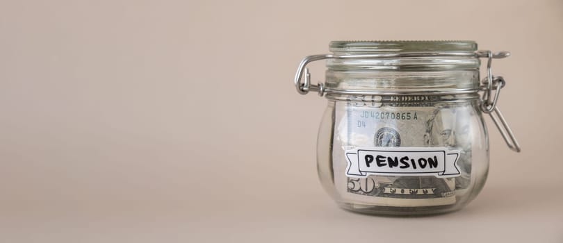Saving Money In Glass Jar filled with Dollars banknotes. PENSION transcription in front of jar. Managing personal finances extra income for future insecurity