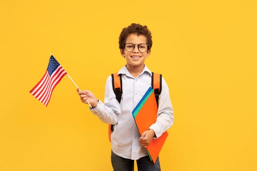 Patriotic schoolboy holding an American flag, ready for school