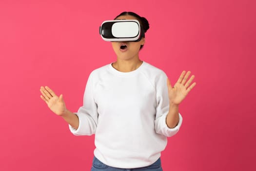 Surprised young asian woman wearing virtual reality headset and gesturing with excitement