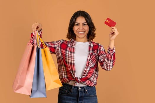 Young arab woman holding credit card and shopping bags