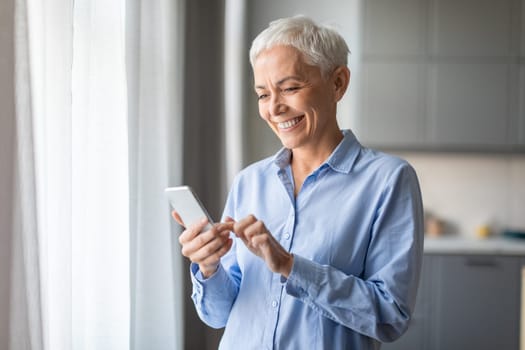 Smiling Senior Lady Using Mobile Phone Texting Standing At Home