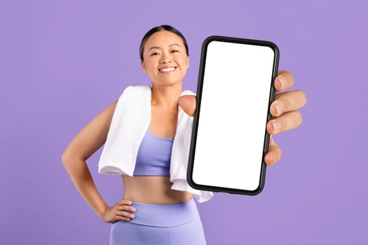 Happy asian woman with towel shows smartphone blank screen
