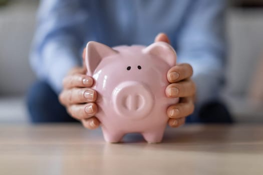 Closeup of female hands holding pink piggybank with retirement savings