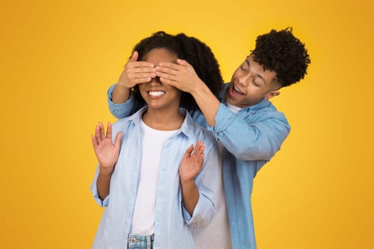 Playful young couple with man covering woman's eyes from behind
