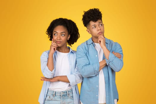 Two thoughtful African American siblings in casual denim attire stand side by side