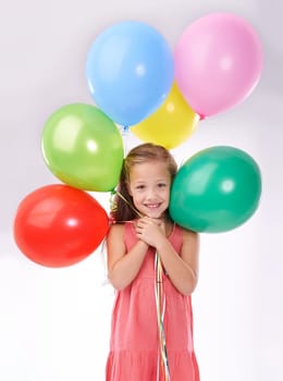 Girl, child and birthday balloons in portrait, party decoration and smiling for milestone event in studio. Happy female person, inflatable accessory and joy on white background, playful and celebrate