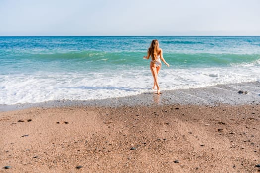 Happy woman in bikini running on the beach. Active leisure, a beautiful girl in a bikini is having fun on the beach, big waves are splashing along the beach.