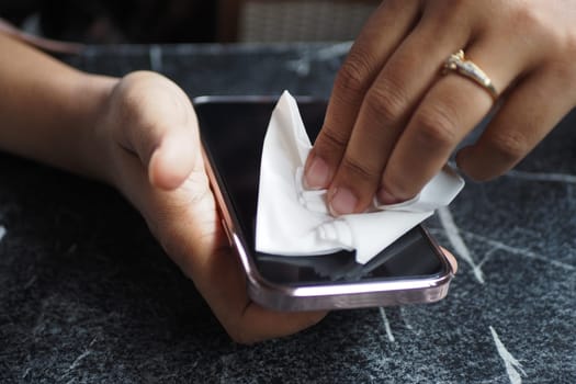 women cleaning mobile phone display with tissue