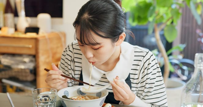 Restaurant, food and Japanese woman with noodles for eating meal, lunch and dinner in cafe. Ramen, cafeteria supper and person with chopsticks for traditional cuisine for health, wellness and hunger.