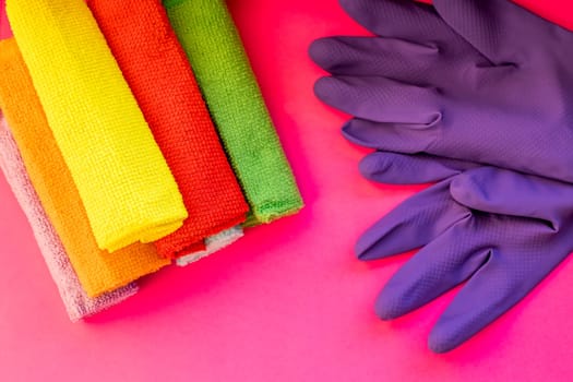 purple rubber gloves, microfiber wipe lying on pink background. cleaning, housecleaning and housework concept, house hygiene and sanitary protection.