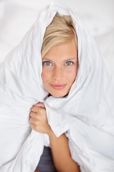 Bed, portrait and blanket to cover woman in morning or home with warm sheet on body. Cosy, girl and duvet on head of person to wake up on holiday or vacation wrapped in linen for comfort in bedroom